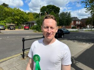 Ben Parry campaigning in Bishopstoke in June 2024. He is wearing a white t-shirt and a Green Party rosette.